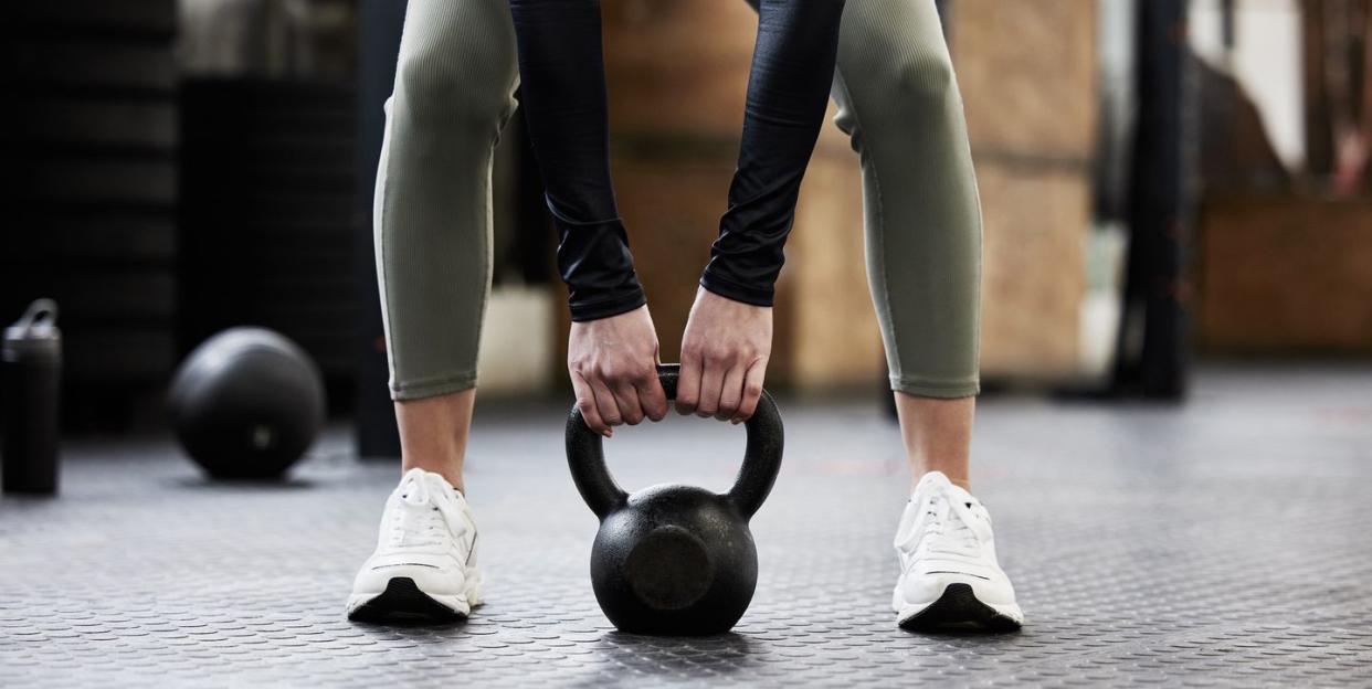 shot of a womans legs as she lifts a kettlebell