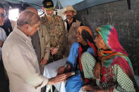 In this handout photo released by Press Information Department, Prime Minister Shahbaz Sharif, left, talks to women inside a tent in the flood-hit area of Suhbatpur in Baluchistan, Pakistan. Sharif on Wednesday promised the country's millions of homeless people that the government will ensure they are paid to rebuild their homes and return to their lives after the country's worst-ever floods. (Press Information Department via AP)