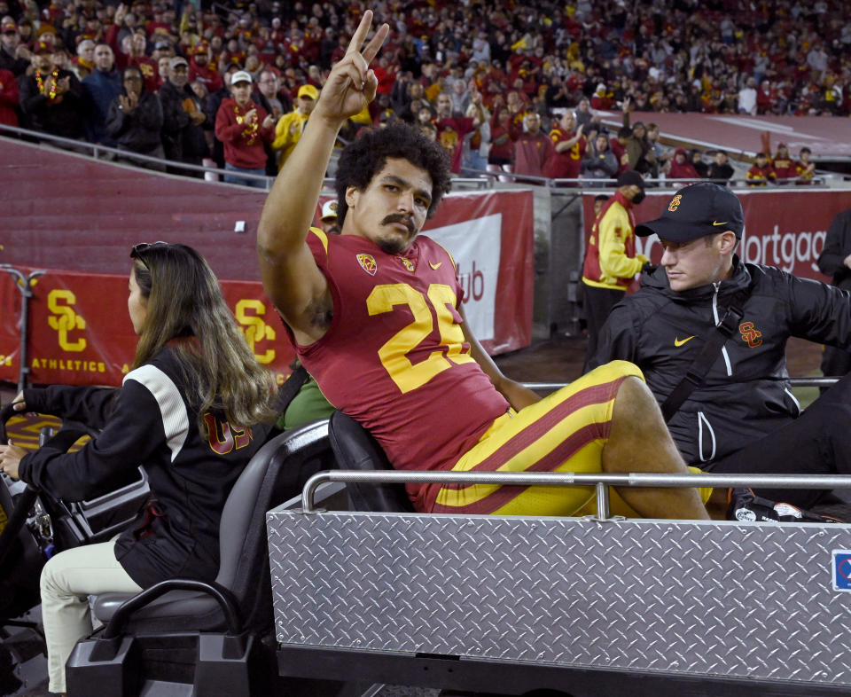 Southern California running back Travis Dye waves to the crowd while being taken off the field on a cart during the first half of the team's NCAA college football game against Colorado on Friday, Nov. 11, 2022, in Los Angeles. (AP Photo/John McCoy)