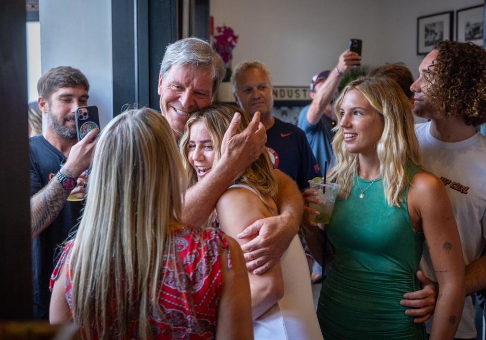 U.S. Olympic surf team member Caroline Marks, center, gets a hug from a supporter.