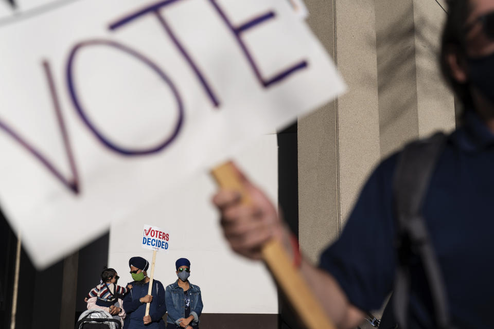 FILE - In this Nov. 7, 2020, file photo, Harjas Singh, 1, reaches out for his father, Umeet Singh, while held by his mother, Preet Kaur, as they attend a rally with their daughter, Nader Kaur, right, celebrating the election results in Detroit. (AP Photo/David Goldman, File)