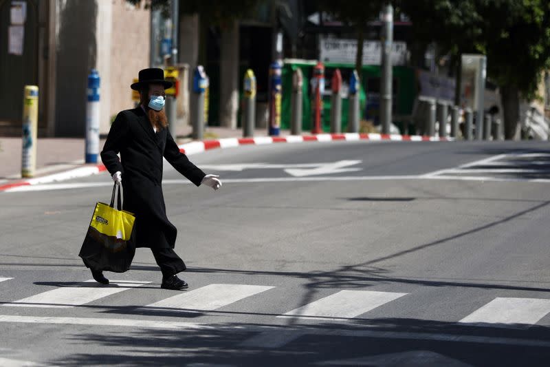 An ultra-Orthodox Jewish man wears a face mask while crossing a street in Bnei Brak as Israel enforces a lockdown of the ultra-Orthodox Jewish town badly affected by coronavirus disease (COVID-19), Bnei Brak