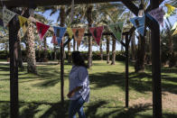 Palm ranch owner Claudia Lua Alvarado walks past a welcome banner in her ranch in Coachella, Calif., Tuesday, June 11, 2024. Lua Alvarado has staked her future on the rows of towering date palms behind the home where she lives with her husband and two children in a desert community east of Los Angeles. (AP Photo/Jae C. Hong)