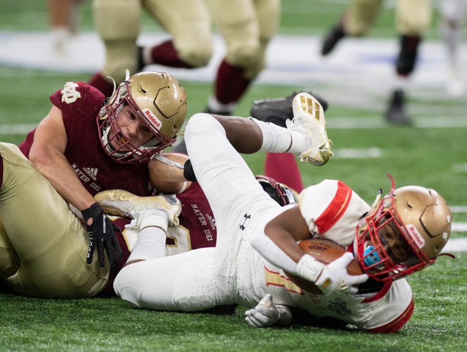 Mater Dei's Spencer Turner (26) and teammate Bryce Humphrey (10) take down Andrean's Alonzo Paul Jr. (1) during the IHSAA Class 2A football state championship between the Mater Dei Wildcats and the Andrean Fighting 59ers at Lucas Oil Stadium in Indianapolis, Ind., Saturday afternoon, Nov. 27, 2021.