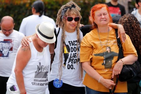 Fans hold one another as they gather at Forest Lawn Cemetery ten years after the death of child star turned King of Pop, Michael Jackson, in Glendale, California