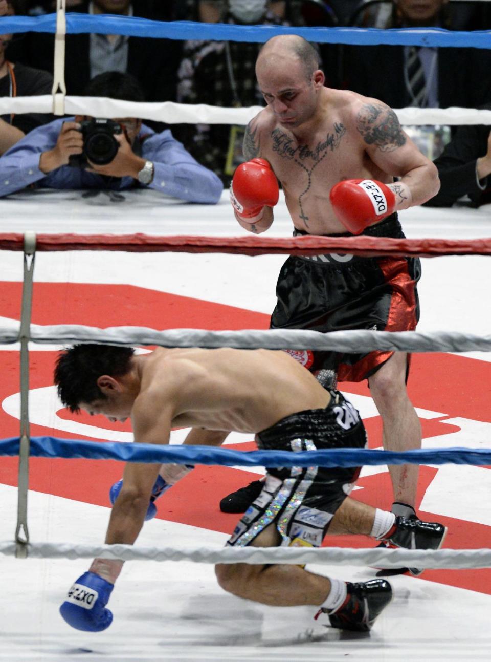 Spanish champion Kiko Martinez looks at Japanese challenger Hozumi Hasegawa kneeling down on the mat in the seventh round of their IBF super bantamweight boxing title bout in Osaka, western Japan, Wednesday, April 23, 2014. Martinez defended his title by technical knockout in the round. (AP Photo/Kyodo News) JAPAN OUT, CREDIT MANDATORY