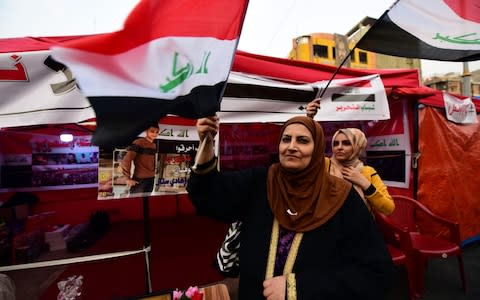 Iraqi protesters carry the Iraqi national flag and shout slogans shortly after the resignation of Iraqi Prime Minister Adel Abdel-Mahdi - Credit: REX