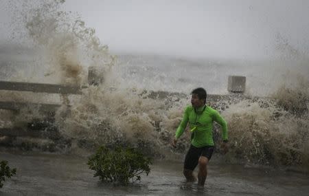 A man playing with waves runs way from a wave at a beach as Typhoon Sarika lands in Wanning, Hainan province, China, October 18, 2016. REUTERS/Stringer