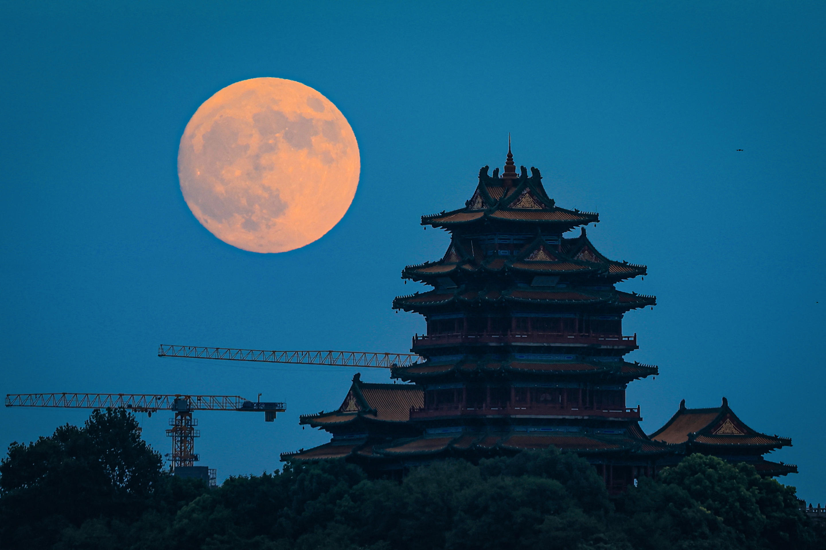 The full moon rises behind the Nanjing Yuejiang Tower in Nanjing, China on Sept. 17 (Stringer/AFP via Getty Images)