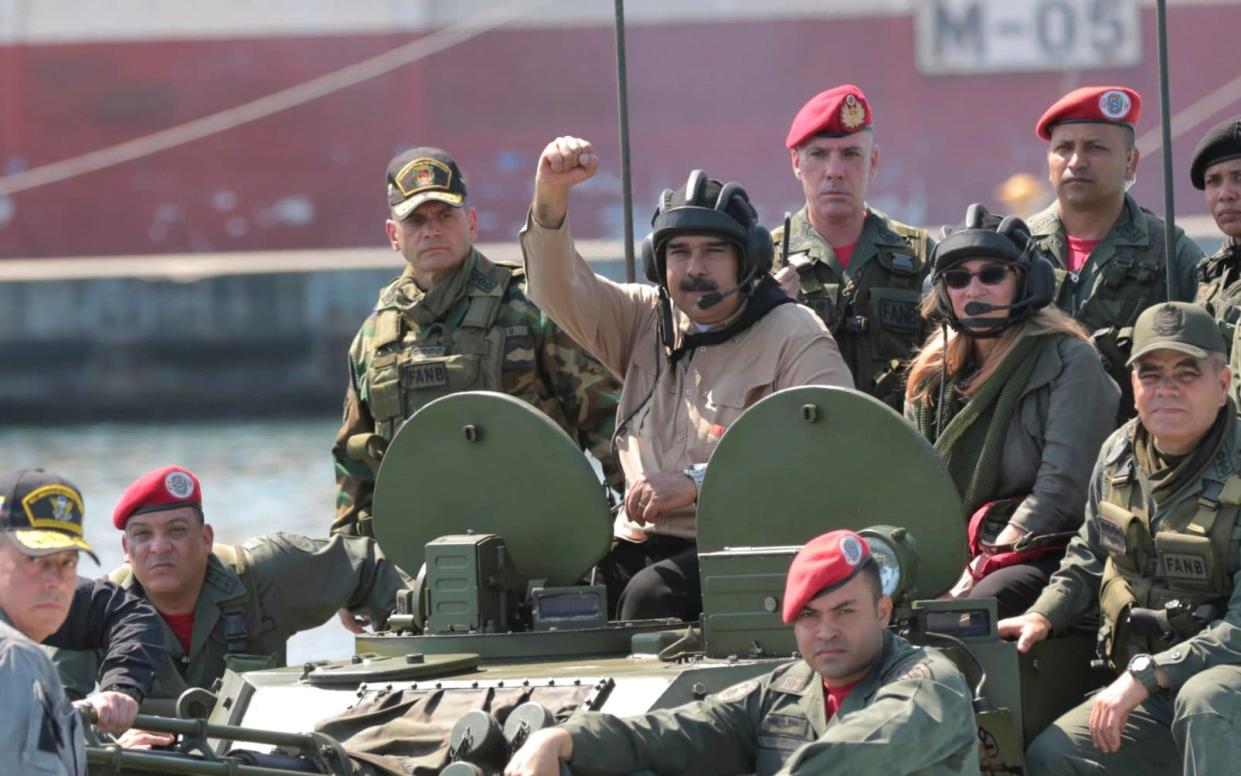 Venezuelan President Nicolas Maduro raises his fist from an amphibious tank as he poses for photos alongside military officers this weekend - Miraflores presidential palace press office via AP