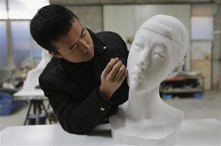 Chinese artist Li Hongbo uses an iron needle to remove dust from a paper sculpture work at his studio on the outskirts of Beijing, January 20, 2014. REUTERS/Jason Lee
