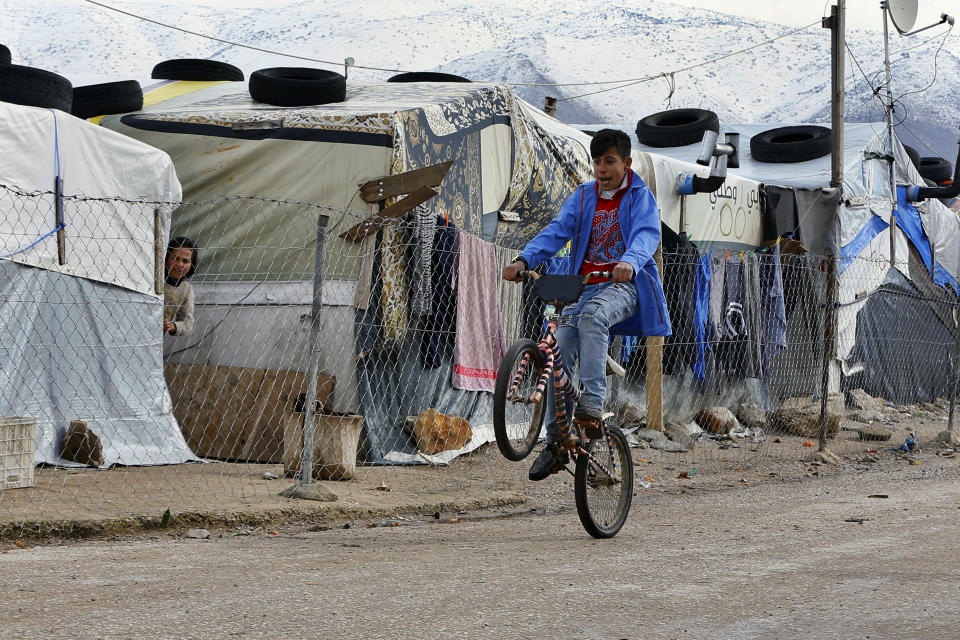 A Syrian refugee rides his bicycle after heavy rain at a refugee camp in the town of Bar Elias, in the Bekaa Valley, Lebanon, Thursday, Jan. 10, 2019. A storm that battered Lebanon for five days has displaced many Syrian refugees after their tents got flooded with water or destroyed by snow. (AP Photo/Bilal Hussein)