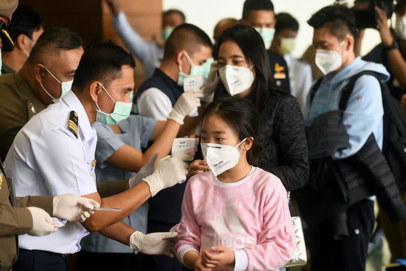 Health workers use infrared thermometers to check the temperature of tourists who arrive at Bangkok's Don Mueang Airport