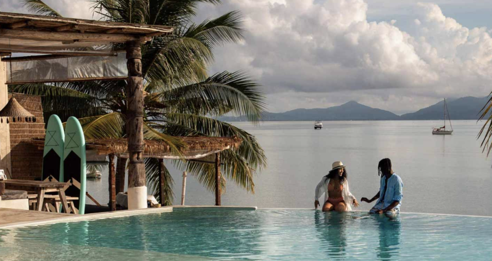 two people sitting on the edge of an infinity pool