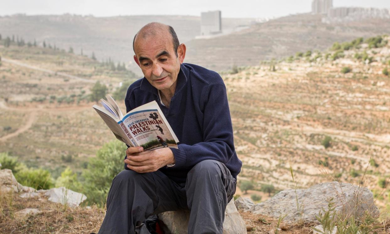 <span>Raja Shehadeh reads his Orwell prize-winning book, Palestinian Walks, outside Ramallah, in the West Bank, 2014.</span><span>Photograph: Rob Stothard/Getty Images</span>