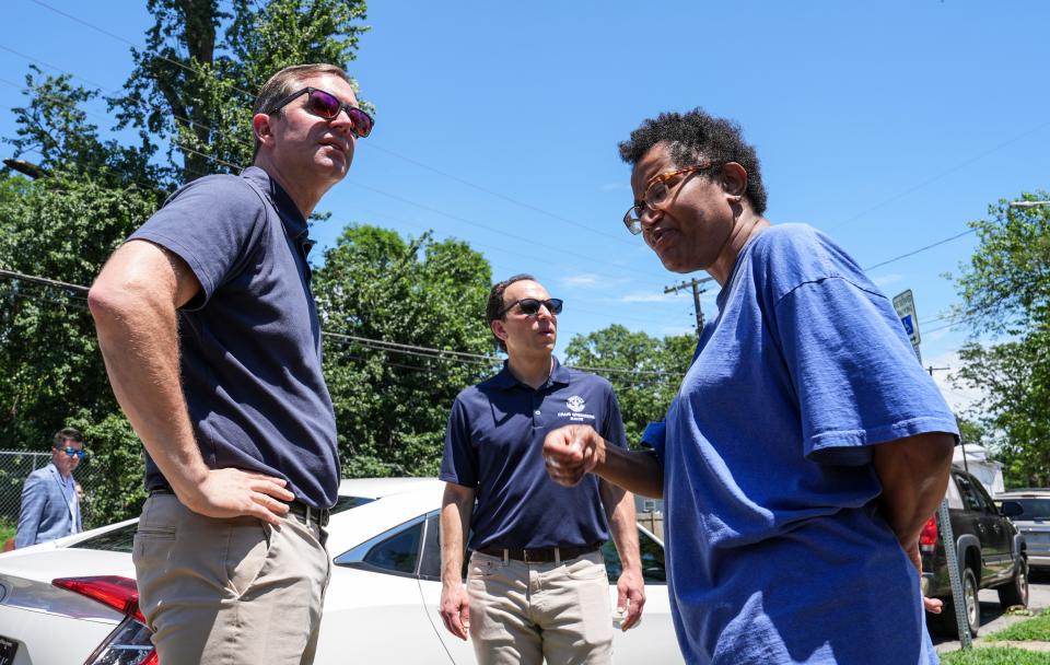 Gov. Andy Beshear talks to Tonya Perry on Woodland Avenue about the storm damage after an E1 tornado on the Fourth of July that hit parts of west Louisville, Kentucky. At center is Louisville mayor Craig Greenburg.