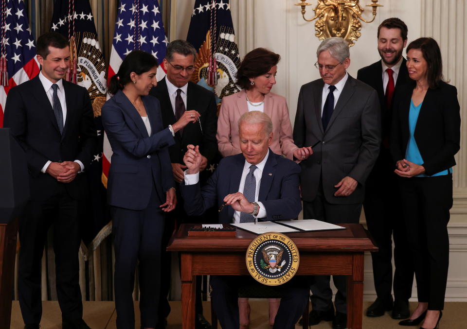 U.S. President Joe Biden hands a pen to Lina Khan, chair of the Federal Trade Commission, while signing an executive order on 