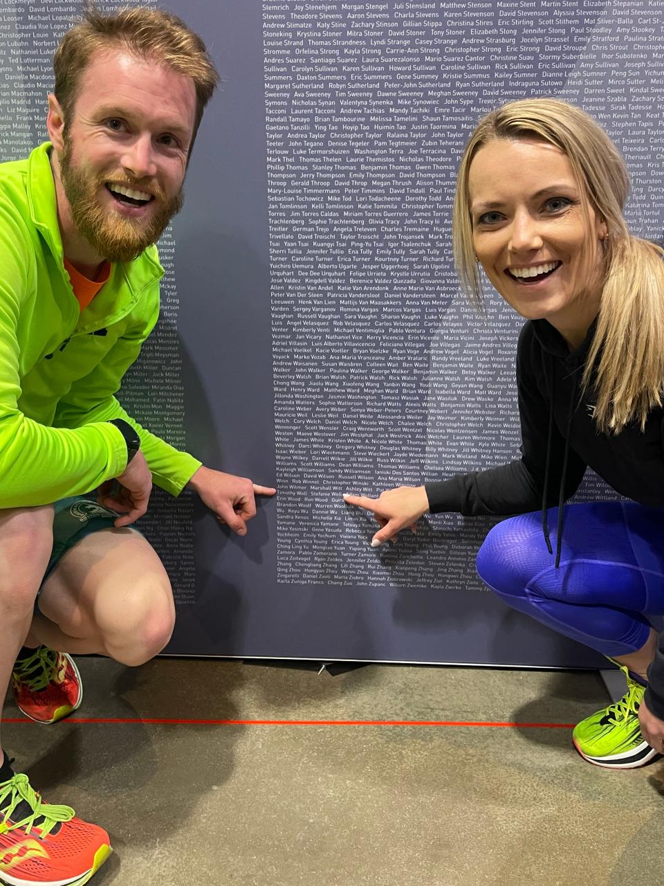 Clay (left) and Stefanie Woll of Howell point to their names on a wall listing the 2023 Boston Marathon entrants.