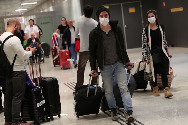 Travellers wearing protective face masks as a precautionary measure arrive on a flight from Italy, after the second case of coronavirus in Sao Paulo was confirmed, at Guarulhos International Airport in Guarulhos