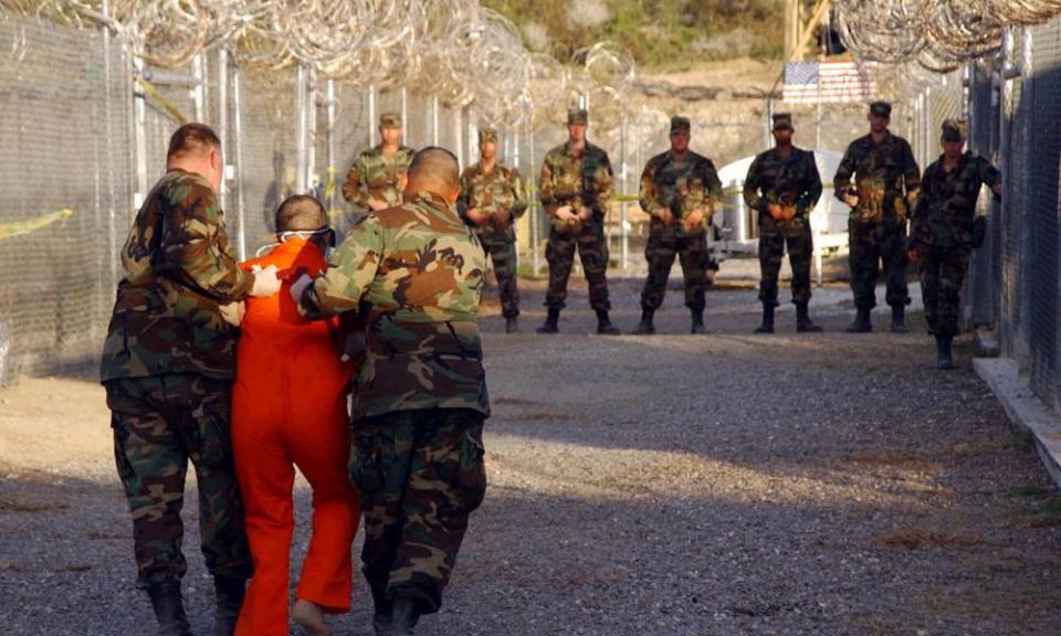 US Army military police escort a detainee to his cell in Camp X-Ray at Guantánamo Bay, Cuba, in 2002