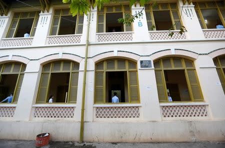 Invigilators stand near a window as students sit for their final examinations at the Sisowath High School in central Phnom Penh, Cambodia, August 22, 2016. REUTERS/Samrang Pring