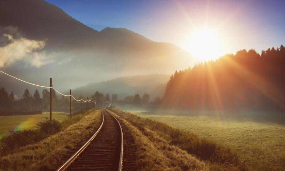 Východ slunce nad železniční tratí v Alpách v Rakousku.