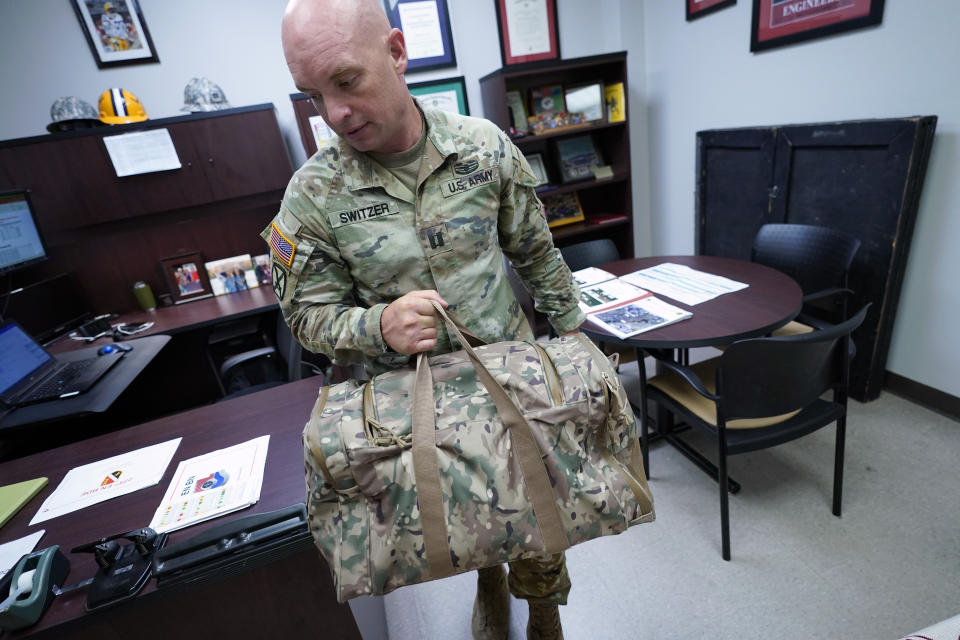 Capt. Michael Switzer goes to change into his sleepwear before going to sleep in his office at Camp Beauregard in Pineville, La., Friday, July 30, 2021. (AP Photo/Gerald Herbert)