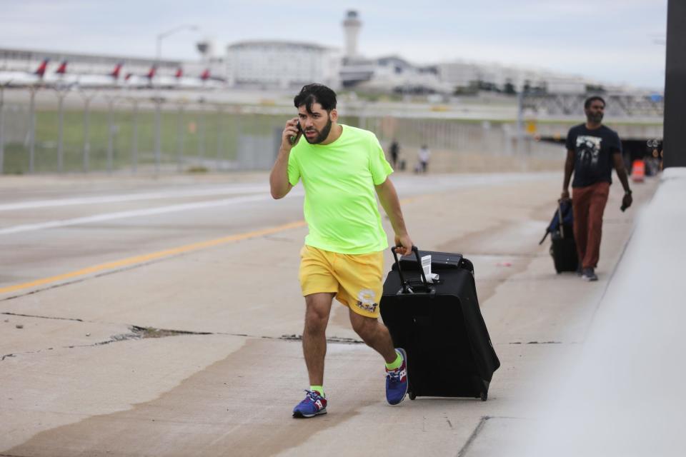 Jerald Joubran, 30, of Hollywood, tries to find his family after his flight landed at McNamara Terminal and he trekked up the road at Detroit Metropolitan Airport, where passengers and would-be travelers were stranded after overnight flooding in the area on Thursday, Aug. 24, 2023.