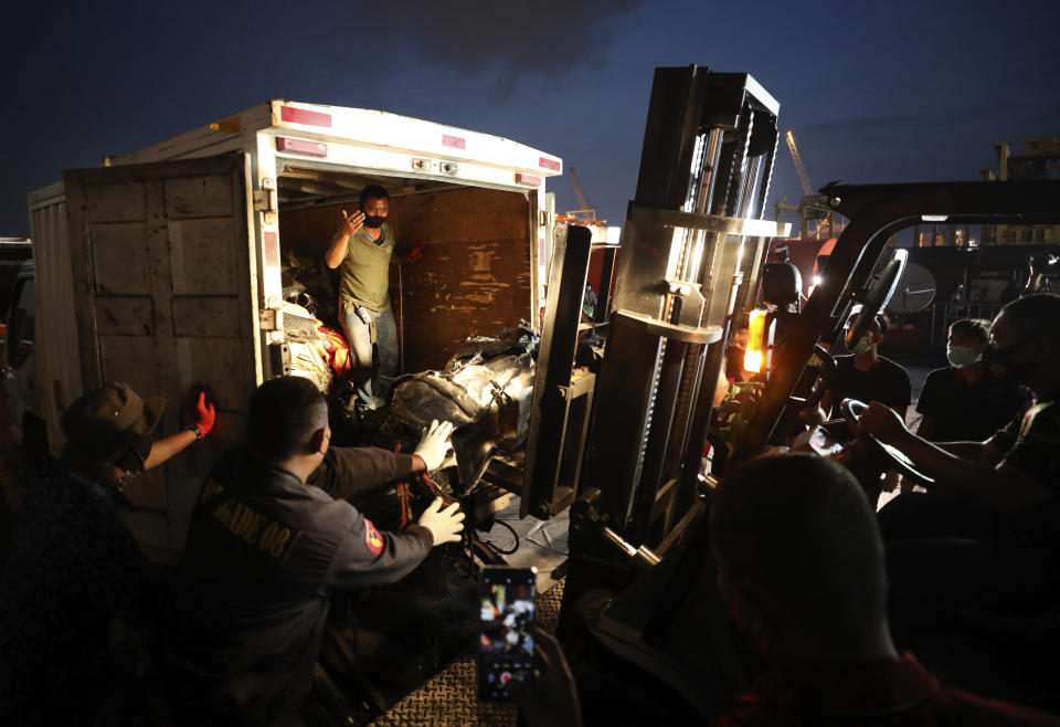 Workers use a forklift to load pieces of wreckage of Sriwijaya Air flight SJ-182 that crashed into the Java Sea on Jan. 9, onto a truck be transported for further investigation, at Tanjung Priok Port in Jakarta, Indonesia, Thursday, Jan. 21, 2021. Indonesian authorities on Thursday ended the search for the wreckage of the plane that nose-dived into the sea, killing all of its passengers on board. (AP Photo/Dita Alangkara)