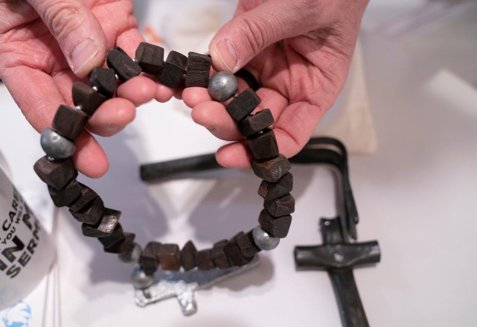 Fr. (the Very Rev.) Chris Yaw of St. David's Episcopal Church shows a piece of art with wood beads made from a gun handle and cross made from the metallic parts of a gun on Friday, March 29, 2024. Yaw has made it his mission to tackle gun violence by initiating gun buyback programs.