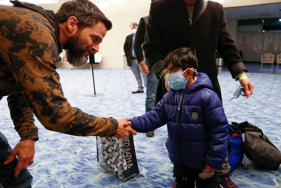 Tommy Breedlove shakes hands with 6-year-old Abdul Bais Noori at the Springfield-Branson National Airport on Monday, Jan. 10, 2022. Noori's dad, who served as a translator for American troops in Afghanistan, fled the country with his family after the troop withdrawal last year.