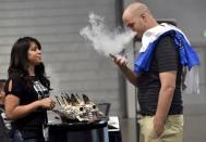 Jerred Marsh (R) samples flavored vape juice from Nancy Reyes at the Vape Summit 3 in Las Vegas, Nevada May 2, 2015. REUTERS/David Becker/File Photo