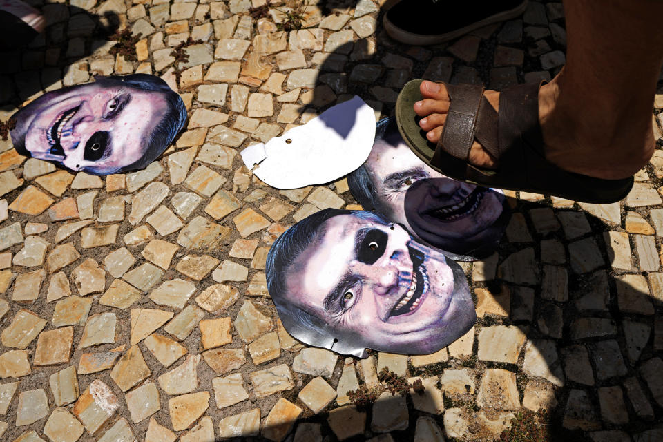 Demonstrators stomp on masks representing Brazilian President Jair Bolsonaro as they protest his government's handling of the COVID-19 pandemic outside Planalto presidential palace in Brasilia, Brazil, Wednesday, Oct. 20, 2021. (AP Photo/Eraldo Peres)