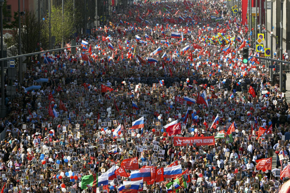 People carry portraits of relatives who fought in World War II, and Russian and Soviet flags, during the Immortal Regiment march through the main street toward Red Square celebrating 74 years since the victory in WWII in Red Square in Moscow, Russia, Thursday, May 9, 2019. (AP Photo/Denis Tyrin)