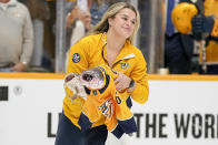 An ice worker skates off the ice with a pair of catfish before the start of Game 6 of an NHL hockey Stanley Cup first-round playoff series between the Nashville Predators and the Vancouver Canucks, Friday, May 3, 2024, in Nashville, Tenn. (AP Photo/George Walker IV)