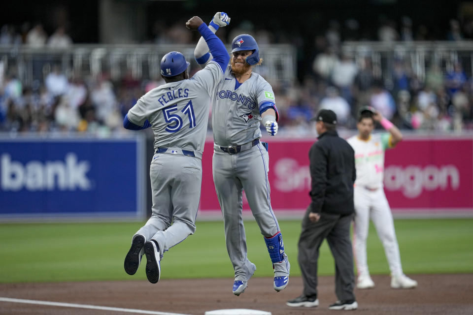 Toronto Blue Jays designated hitter Justin Turner, center, celebrates with third base coach Carlos Febles (51) after hitting a home run during the first inning of a baseball game against the San Diego Padres, Friday, April 19, 2024, in San Diego. (AP Photo/Gregory Bull)