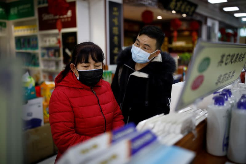 People wearing face masks look for products at a pharmacy as the country is hit by an outbreak of the new coronavirus