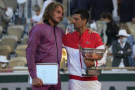 Serbia's Novak Djokovic ,right, and Stefanos Tsitsipas of Greece hold their trophies after their final match of the French Open tennis tournament at the Roland Garros stadium Sunday, June 13, 2021 in Paris. Djokovic won 6-7 (6), 2-6, 6-3, 6-2, 6-4. (AP Photo/Michel Euler)