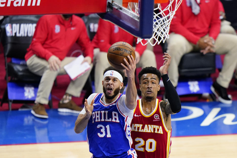 Philadelphia 76ers' Seth Curry, left, goes up for a shot past Atlanta Hawks' John Collins during the first half of Game 2 in a second-round NBA basketball playoff series, Tuesday, June 8, 2021, in Philadelphia. (AP Photo/Matt Slocum)