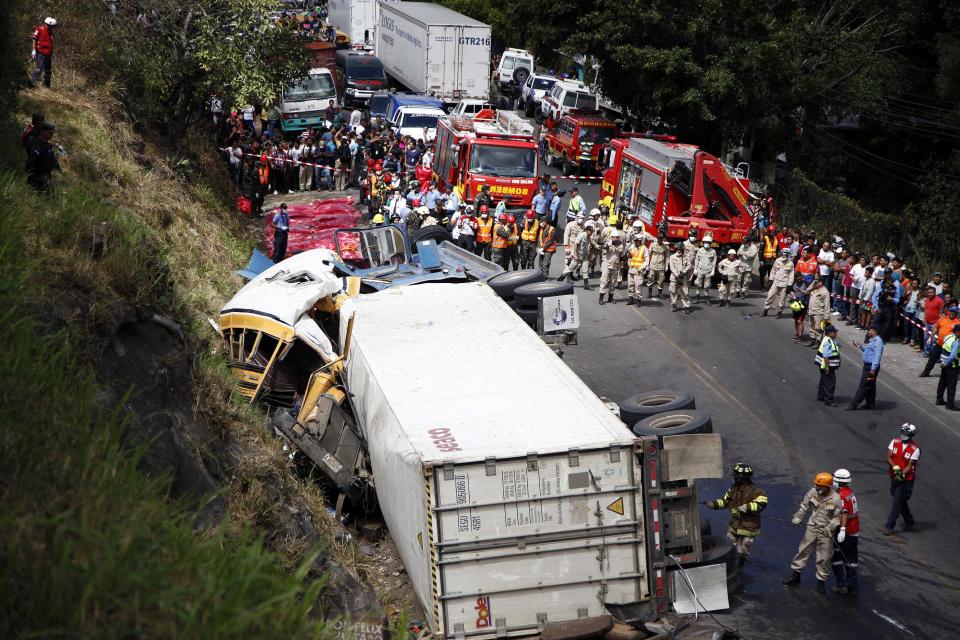 Emergency personnel respond to an accident involving a cargo truck and bus on the outskirts of Tegucigalpa, Honduras, Sunday, Feb. 5, 2017. The cargo truck crashed into the bus on the highway outside Honduras' capital Sunday, killing more than a dozen people, authorities said. Police said the truck driver fled after the crash on a highway that links the capital with southern Honduras. (AP Photo/Fernando Antonio)
