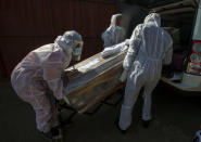 FILE - In this July 21 2020, file photo, funeral home workers in protective suits carry the coffin of a woman who died from COVID-19 into a hearse in Katlehong, near Johannesburg, South Africa. Africa’s confirmed coronavirus cases have surpassed 1 million, but global health experts tell The Associated Press the true toll is several times higher. (AP Photo/Themba Hadebe, File)