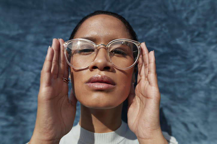 A woman framing her face and adjusting her glasses