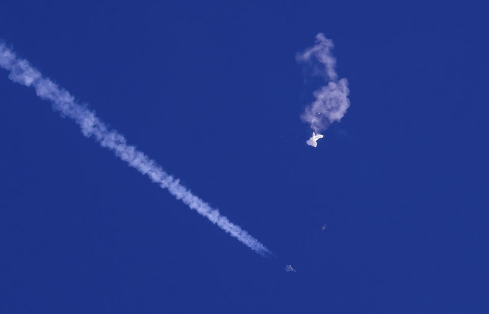 Fotografía proporcionada por Chad Fish de los restos de un globo cayendo sobre el océano Atlántico frente a la costa de Carolina del Sur (arriba a la derecha), mientras abajo se observa un avión de combate y su estela, el sábado 4 de febrero de 2023. (Chad Fish vía AP)