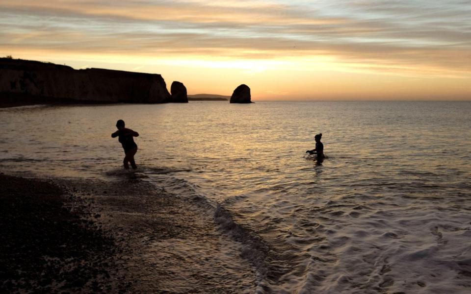 Sunrise wild swimming swimmers in the sea at Freshwater Bay on the Isle of Wight - Alamy