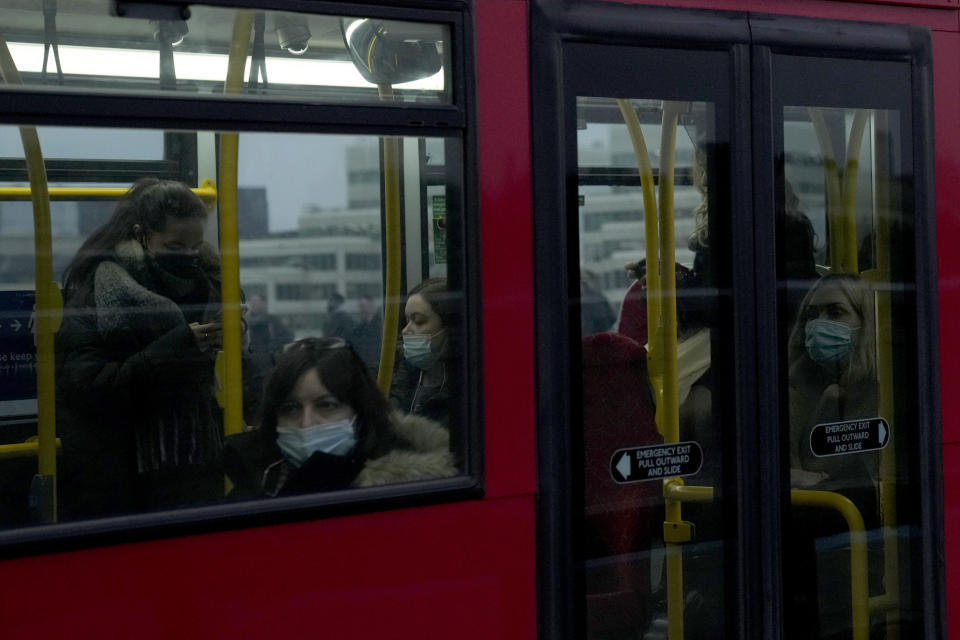 People wear face masks to curb the spread of coronavirus, which is still a mandatory requirement on Transport for London public transport services, as they travel on a bus going over London Bridge towards the City of London financial district during the morning rush hour in London, Monday, Jan. 24, 2022. The British government have asked people to return to working in offices starting Monday as they ease coronavirus restrictions. (AP Photo/Matt Dunham)