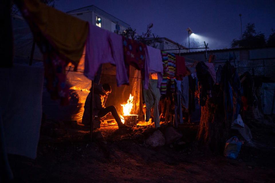 A migrant tries to warm himself in a temporary camp next to the camp in Moria by a small fire on January 22, 2020. | Angelos Tzortzinis–Getty