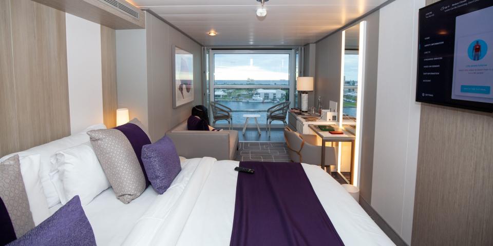 the bed, TV, and living room in front of a glass wall