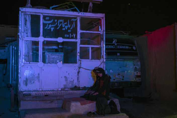 Two Afghan men pray at a bus station in Herat, Afghanistan, on Tuesday, Nov. 23, 2021, before they embark on a bus for a 300-mile trip south to Nimrooz near the Iranian border. Afghans are streaming across the border into Iran, driven by desperation after the near collapse of their country's economy following the Taliban's takeover in mid-August. In the past three months, more than 300,000 people have crossed illegally into Iran, according to the Norwegian Refugee Council, and more are coming at the rate of 4,000 to 5,000 a day. (AP Photo/Petros Giannakouris)
