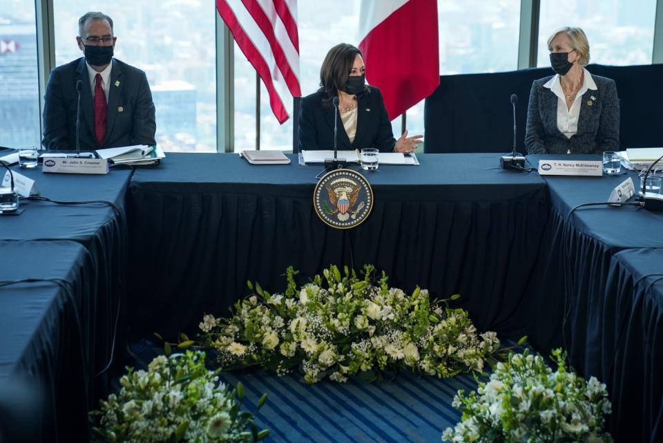 Kamala Harris sits at a table flanked by two advisors.