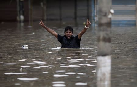 A man shouts religious slogans as he wades through a flooded street in Srinagar September 12, 2014. REUTERS/Adnan Abidi